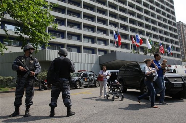 Police stand guard as tourists evacuate the Intercontinental Hotel in Rio de Janeiro, Brazil, on Saturday after it was invaded by gunmen who took hostages.